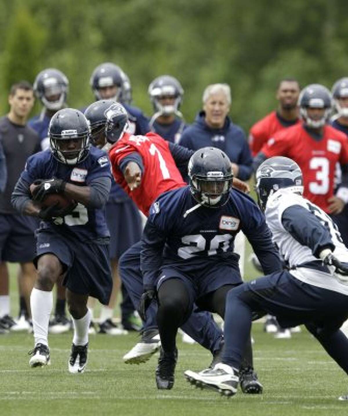 Seattle Seahawks' Leon Washington, left, takes a handoff from quarterback Tavaris Jackson, second from left, as Kregg Lupkin (20) squares off to block Heath Farwell, right, during practice Thursday, June 14, 2012, in Renton. (Ted S. Warren / Associated Press)