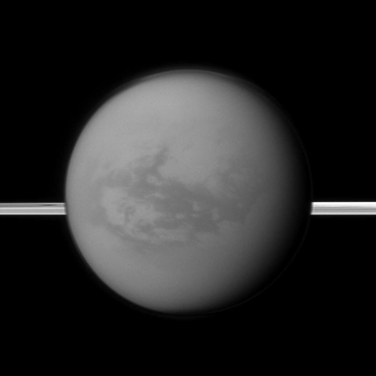 This image provided by NASA shows Titan with Saturn's rings in the background. A new study being released on Thur. June 14, 2012 suggests the dark areas near Titan's equator indicate the presence of a hydrocarbon lake and several ponds, a surprise to scientists who thought lakes only existed at the poles. (AP Photo/NASA)