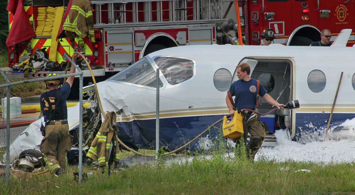 Officials inspect a downed aircraft Monday, June 18, 2012, near Atlanta. Authorities say all four people aboard a small jet were hurt when the aircraft ran off a runway in the Atlanta area. Federal Aviation Administration spokeswoman Kathleen Bergen says four people were on board the Hawker Beechcraft 40 that crashed through a fence after leaving the runway at DeKalb-Peachtree Airport around 10 a.m. Monday. (AP Photo/Atlanta Journal-Constitution, John Spink)