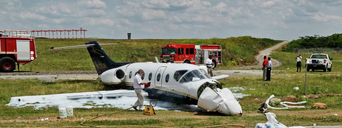 Officials inspect a downed aircraft Monday, June 18, 2012, near Atlanta. Authorities say all four people aboard a small jet were hurt when the aircraft ran off a runway in the Atlanta area. Federal Aviation Administration spokeswoman Kathleen Bergen says four people were on board the Hawker Beechcraft 40 that crashed through a fence after leaving the runway at DeKalb-Peachtree Airport around 10 a.m. Monday. (AP Photo/Atlanta Journal-Constitution, John Spink)