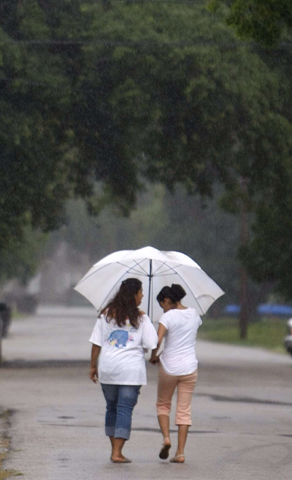 Florinda Rangel and her daughter Monserrat, 16, walk home in the rain Tuesday near the corner of Elgin and Bastrop.