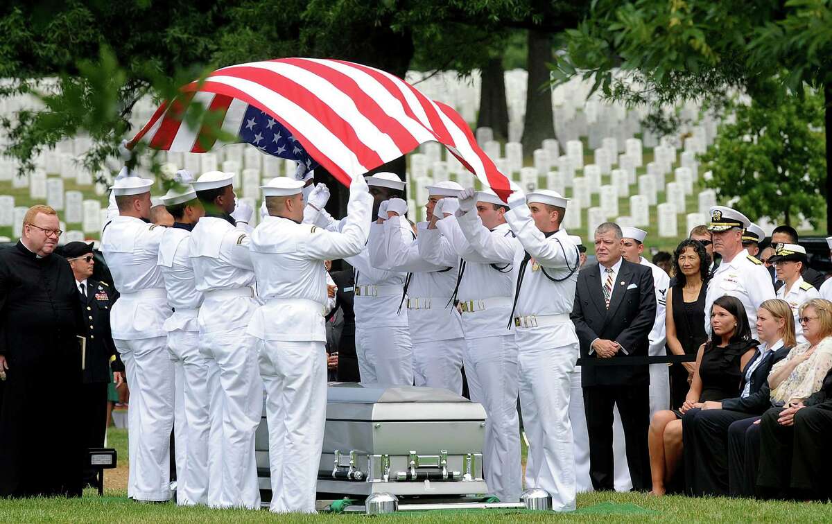 Honor guard team folds the American flag over the casket of U.S. Navy Petty Officer 2nd Class Sean E. Brazas of Greensboro, North Carolina, June 19, 2012 at Arlington National Cemetery in Arlington, Virginia. Brazas was killed last month in Afghanistan by an enemy sniper while he was helping his unit board a helicopter.