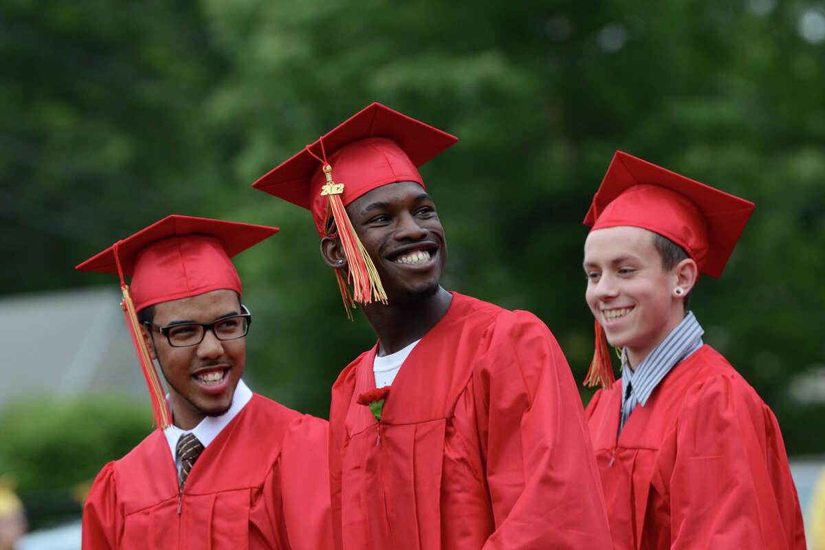 Jordan Reese Crumpton, center, flashes a smile to the crowd as he walks with fellow graduate Corey Ilidio Leite, left, during Stratford High School's 123rd Commencement at Penders Field in Stratford on Tuesday, June 19, 2012.