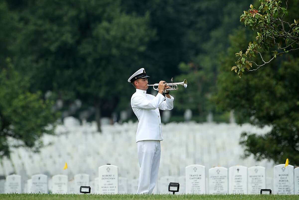 ARLINGTON, VA - JUNE 19: Bugler Gunnar R. Bruning plays "Taps" during the burial of U.S. Navy Petty Officer 2nd Class Sean E. Brazas June 19, 2012 at Arlington National Cemetery in Arlington, Virginia. Petty Officer Brazas, a K-9 handler, was killed while being ambushed as he was helping a fellow officer into a helicopter in Panjawâ€™l, Afghanistan on May 30, 2012. (Photo by Alex Wong/Getty Images)