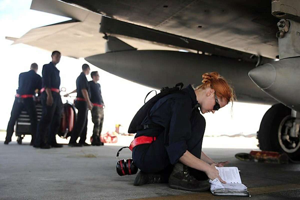 Airman 1st Class Jessica Hinves, US Air Force, kneels under an aircraft, from THE INVISIBLE WAR, a Cinedigm/Docurama Films release.