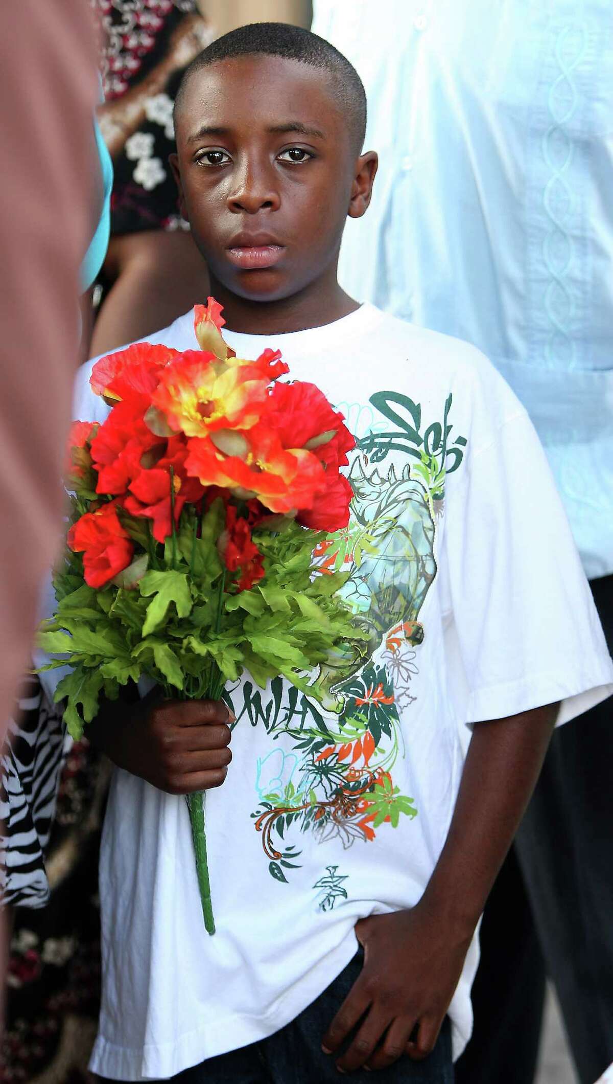 Tiger Polk, 10, holds flowers for his family member Erica Dotson, 29, during a vigil at the scene of a strip club at 9850 Westpark, where three people, including Dotson, were shot to death and two were injured including local rapper Trae Tha Truth, early Wednesday morning, Wednesday, June 20, 2012, in Houston.