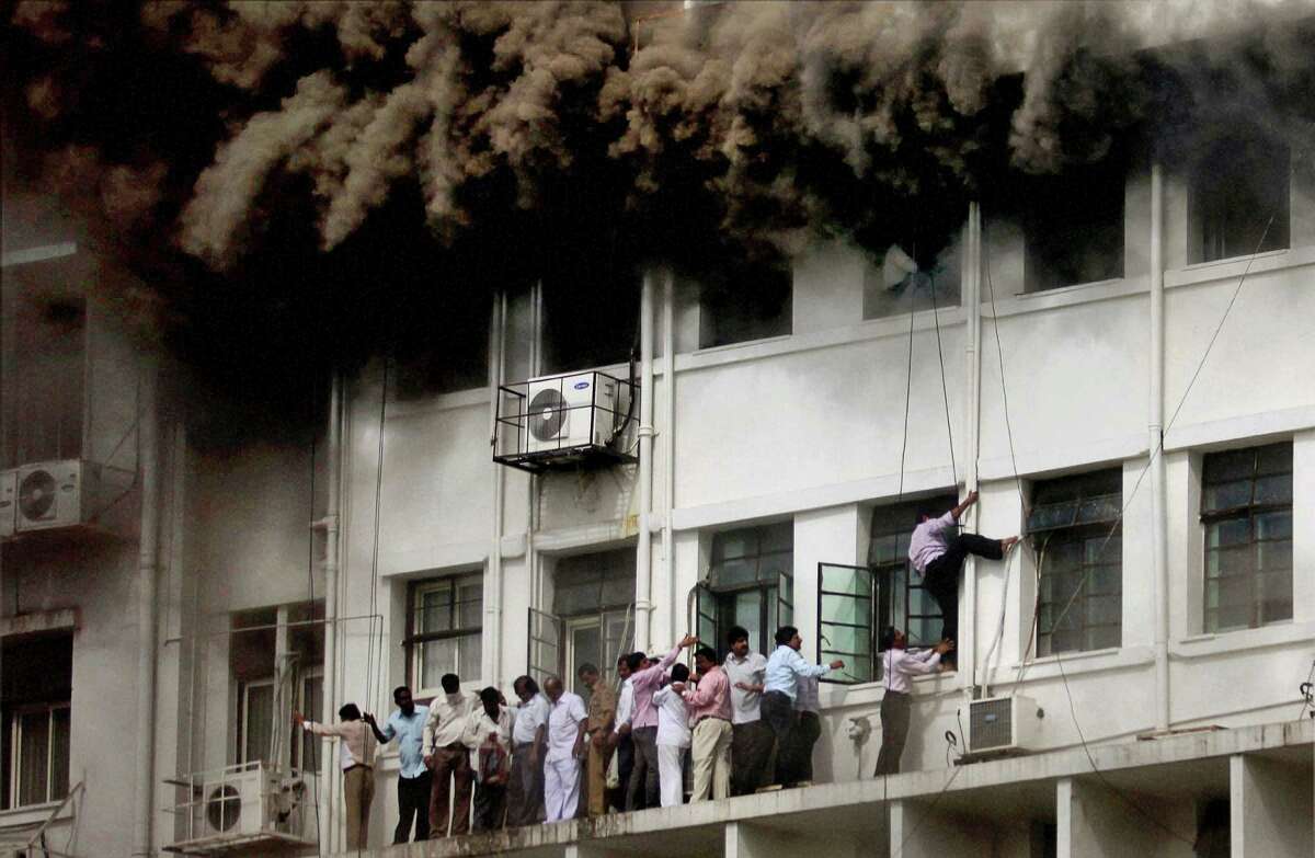Indian employees are evacuated as smoke billows after the Maharashtra state government caught fire in Mumbai, India, Thursday, June 21, 2012. Hundreds of employees were evacuated Thursday from the seven-story government building as more than two dozen fire engines battled the major fire that raged for more than three hours in India's financial and entertainment capital. (AP Photo)
