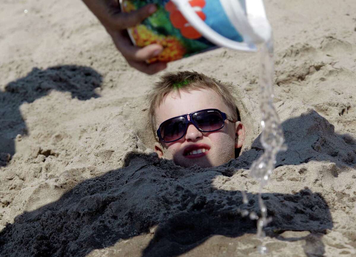 Water is pored over Andrey Krivetc, 11, while he is buried in the sand in the Brighton Beach section of Brooklyn in New York, Thursday, June 21, 2012. In New York and Washington, D.C., temperatures reached 94 degrees before noon Thursday. Philadelphia was 93 degrees and climbing, and Boston hit 92 degrees. With the heat index added in, the air felt several degrees hotter. (AP Photo/Seth Wenig)