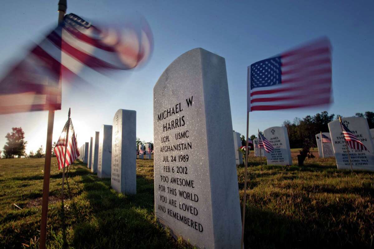 American flags wave near the grave of Marine Lance Cpl. Michael Harris as the the sun rises over Georgia National Cemetery on Memorial Day, Monday, May 28, 2012, in Canton, Ga. Harris died Feb. 6, 2012, in North Carolina.