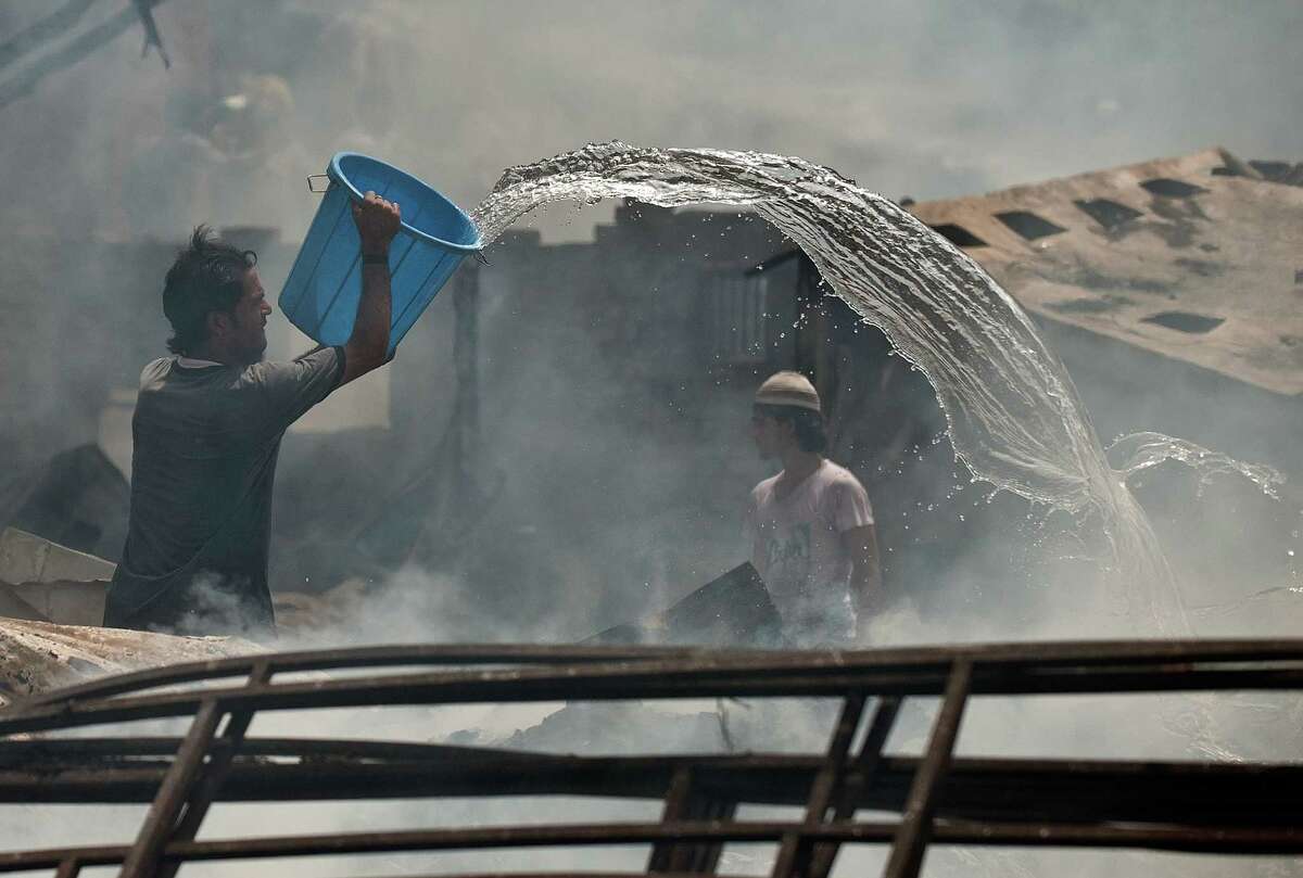 A resident helps extinguish a fire at a slum cluster in New Delhi on June 22, 2012.