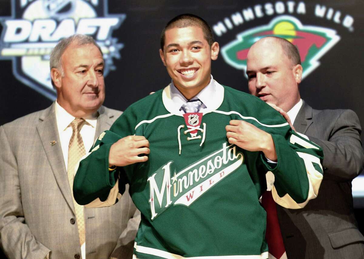 Matthew Dumba, center, a defenseman, smiles with officials from the Minnesota Wild after being chosen seventh overall in the first round of the NHL hockey draft on Friday, June 22, 2012, in Pittsburgh. (AP Photo/Keith Srakocic)