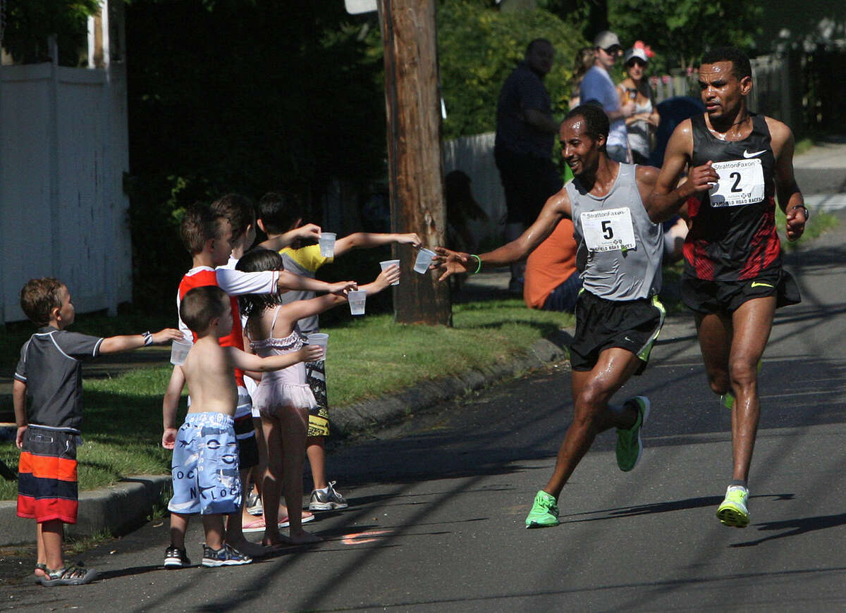 Tesfaye Girma, 5, of Ethiopia, takes water along the route of the annual Stratton Faxon Fairfield Half Marathon in Fairfield, Conn. on Sunday, June, 24, 2012.
