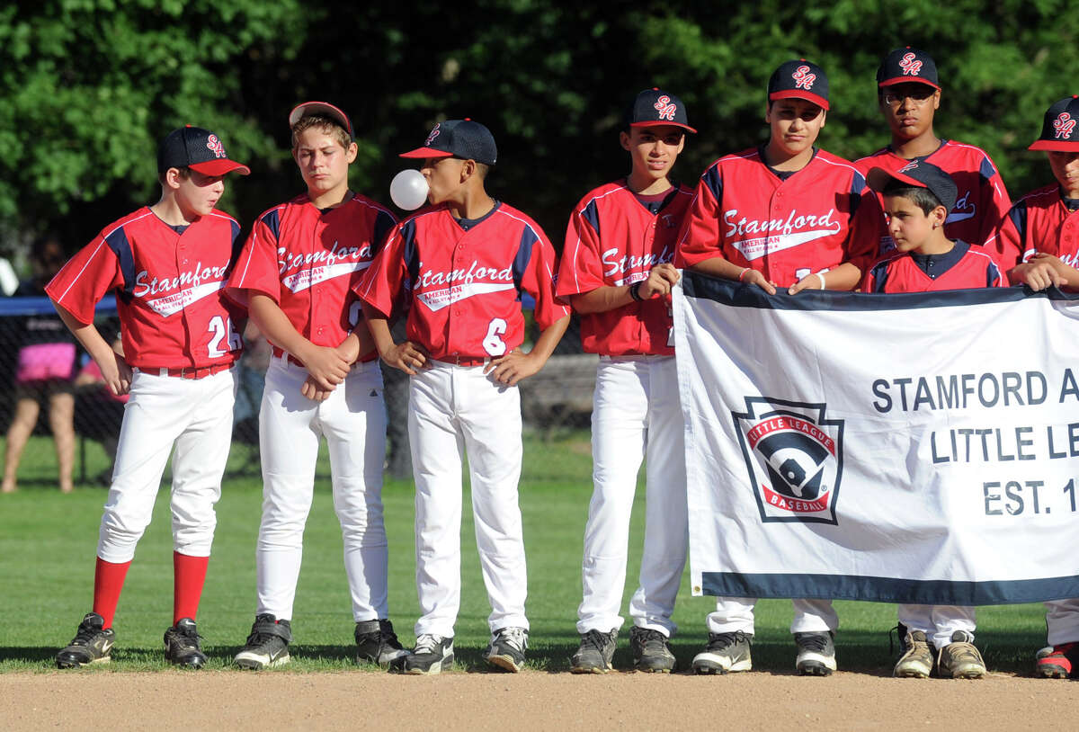 Chris Rojas, center, blows bubbles as he and teammates from the Stamford American Little League team attend the Little League Opening Ceremonies at Springdale's Drotor Field in Stamford, Conn., June 26, 2012.