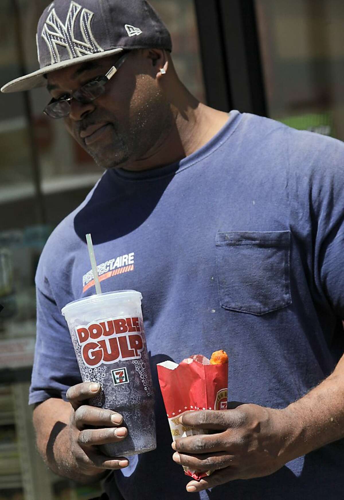 A man leaves a 7-Eleven store with a Double Gulp drink, in New York, Thursday, May 31, 2012. New York Mayor Michael Bloomberg is proposing a ban on the sale of large sodas and other sugary drinks in the city's restaurants, delis and movie theaters in the hopes of combating obesity, an expansion of his administration's efforts to encourage healthy behavior by limiting residents' choices. (AP Photo/Richard Drew)