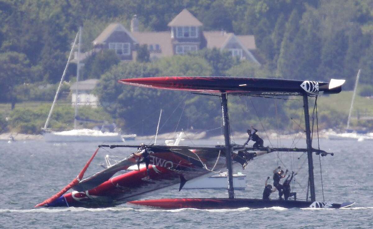 Team New Zealand crew members hang on as they attempt to right their ship after their boat capsized during a match race at the first day of the America's Cup World Series regatta in Newport, R.I., Thursday, June 28, 2012. (AP Photo/Stephan Savoia)
