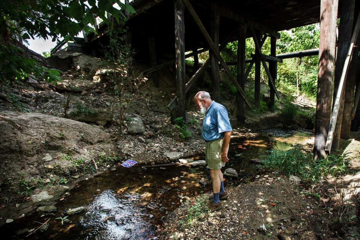 Jim Ohmart checks the water quality of Japhet Creek running through the Japhet Creek Community, Thursday, June 14, 2012, in Houston. Although just a few miles from downtown Houston, Japhet Creek Community feels more like the country and it operates in a way that allows the residents to be less dependent on the commercial world. Jim Ohmart started this community and owns most of the properties. ( Michael Paulsen / Houston Chronicle )