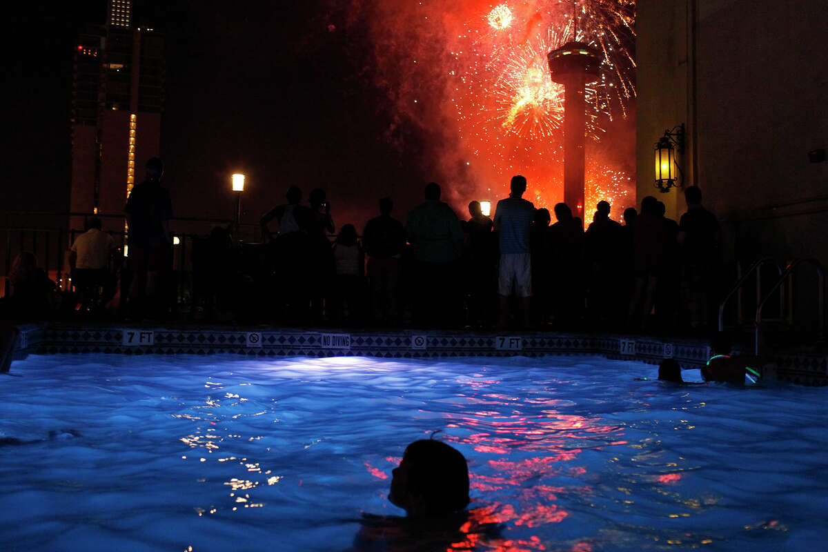 Children swim and people watch fireworks from the Hilton Palacio del Rio pool during the Stars & Stripes over San Antonio inaugural event on Wednesday, July 4, 2012.
