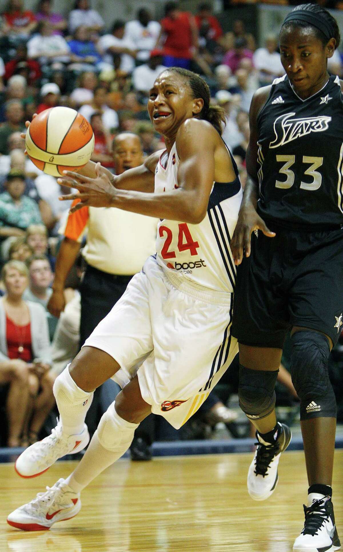 Indiana Fever's Tamika Catchings (24) drives against San Antonio Stars' Sophia Young (33) during the first half of a WNBA basketball game, Thursday, July 5, 2012, in Indianapolis.