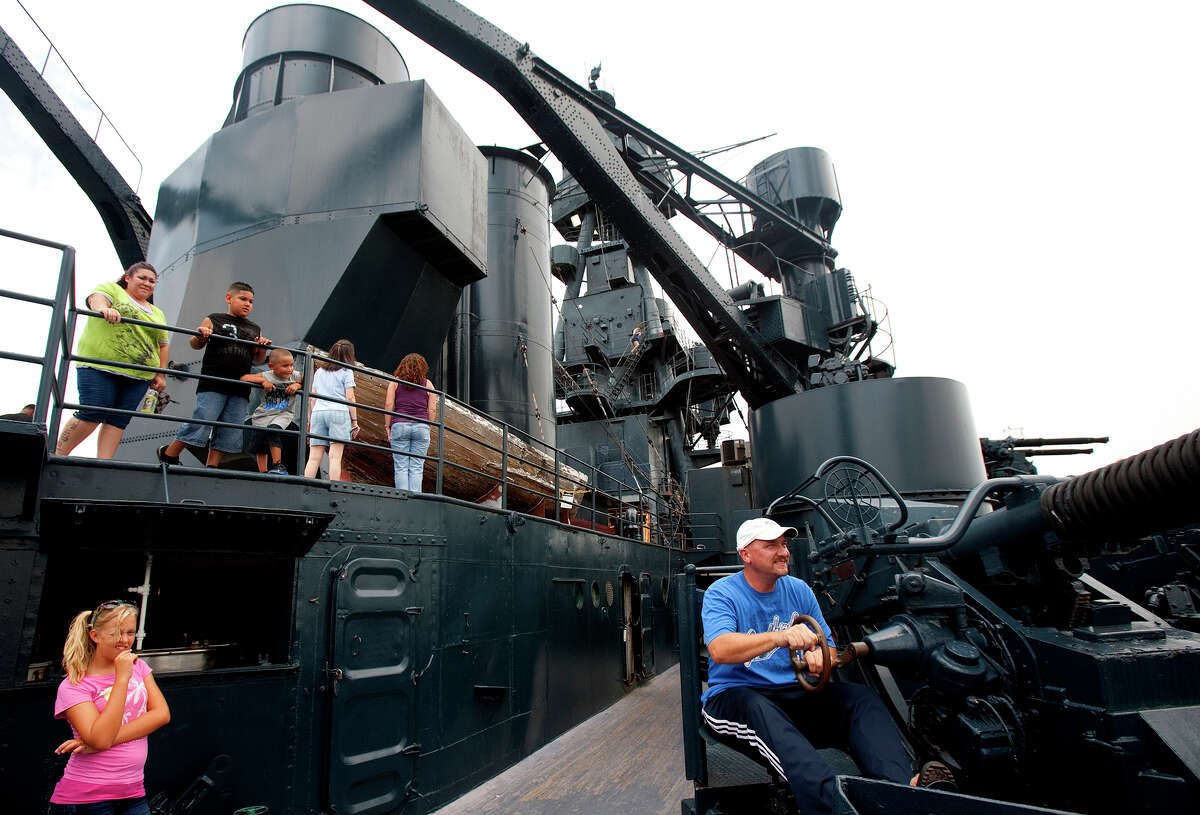 Mackenzie Erdley, 12, left, watches as her father, Steve Erdley, right, operates a 40mm Bofors antiaircraft gun atop the Battleship Texas Saturday, July 7, 2012, in La Porte. The state historic site reopened to the public Saturday after being closed since June 24 for repairs to fix leaks in the vessel's metal hull.