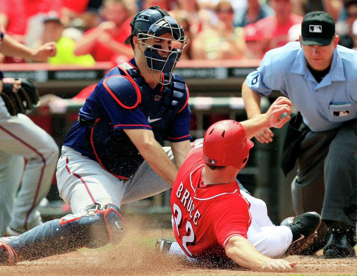 Minnesota Twins' catcher Joe Mauer tags out Cincinnati Reds' Jay Bruce (32) at home in the sixth inning of a baseball game, Sunday, June 24, 2012, in Cincinnati. Minnesota won 4-3. Home plate umpire Mike Muchlinski watches the play. (AP Photo/Al Behrman)