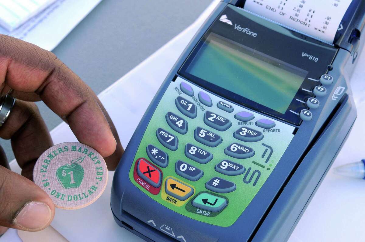 An EBT token is held next to the machine used to swipe EBT cards at the Empire State Plaza Farmers' Market on Wednesday, July 11, 2012 in Albany, NY. The market began accepting food stamp/EBT cards. Those using the EBT card will go to the manager of the market and their card will be swiped and then the shopper will receive EBT tokens to use as money to purchase eligible items. The Empire State Farmers' Market is held on Wednesdays and Fridays from 10 a.m. to 2 p.m. (Paul Buckowski / Times Union)