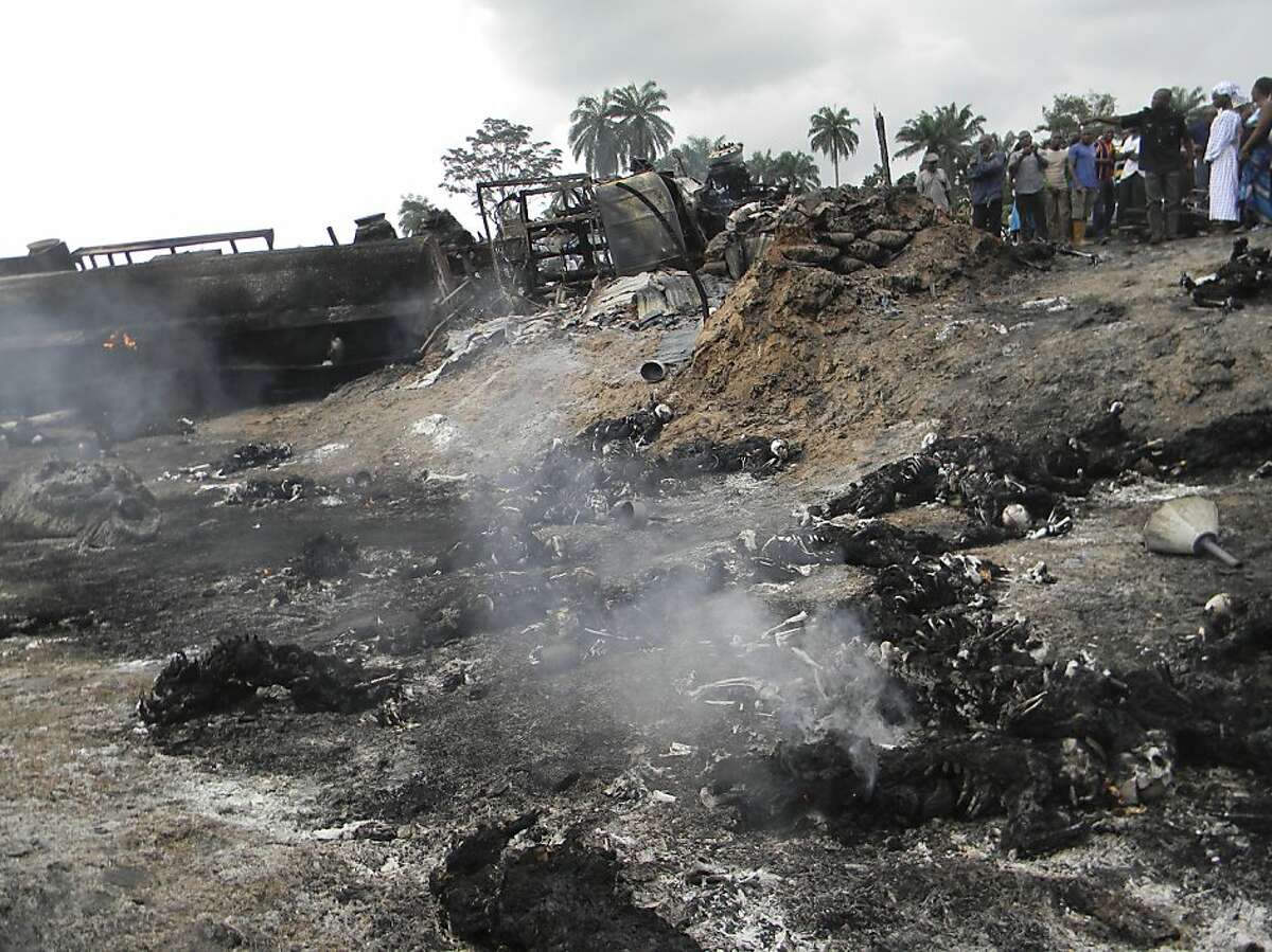People look at charred bodies following fuel tanker explosion in Okogbe near Port Harcourt Nigeria, Thursday, July 12, 2012. A truck carrying fuel caught fire and exploded in Nigeria on Thursday after it veered off the road into a ditch, killing at least 95 people who had rushed to the scene to scoop fuel that had spilled, an official said.(AP Photo)