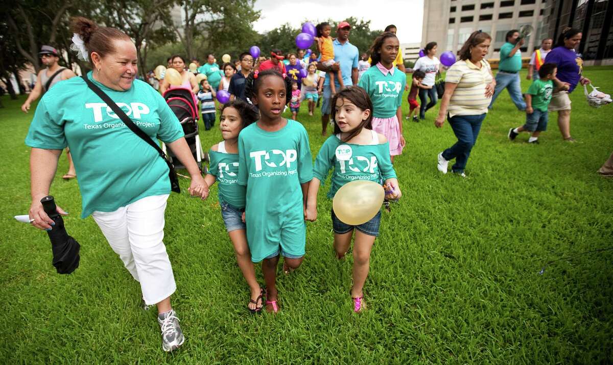 Sylvia Lugo, left, walks with her granddaughter Jasmyn Rodriguez, her friend Madison Hermann, center, and other granddaughter Jizel Rodriguez to a Post Oak Blvd. protest for pay wages for janitors during a City Wide Children's Day of Action.