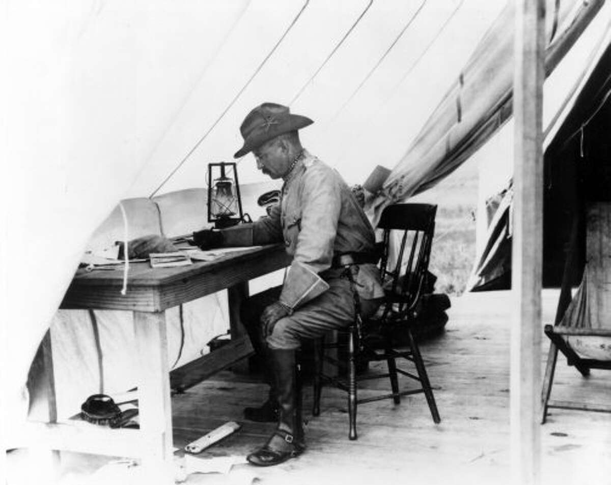 Theodore Roosevelt working at a desk inside his tent in San Antonio, Texas, during the training of the Rough Riders in 1898.