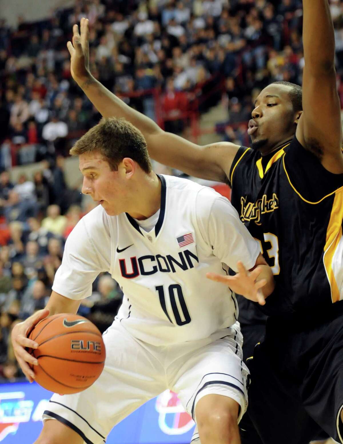 Connecticut's Tyler Olander, left, is defended by American International's Braxton Gardner in the first half of an NCAA college exhibition basketball game Wednesday, Nov. 2, 2011, in Storrs, Conn. (AP Photo/Bob Child)