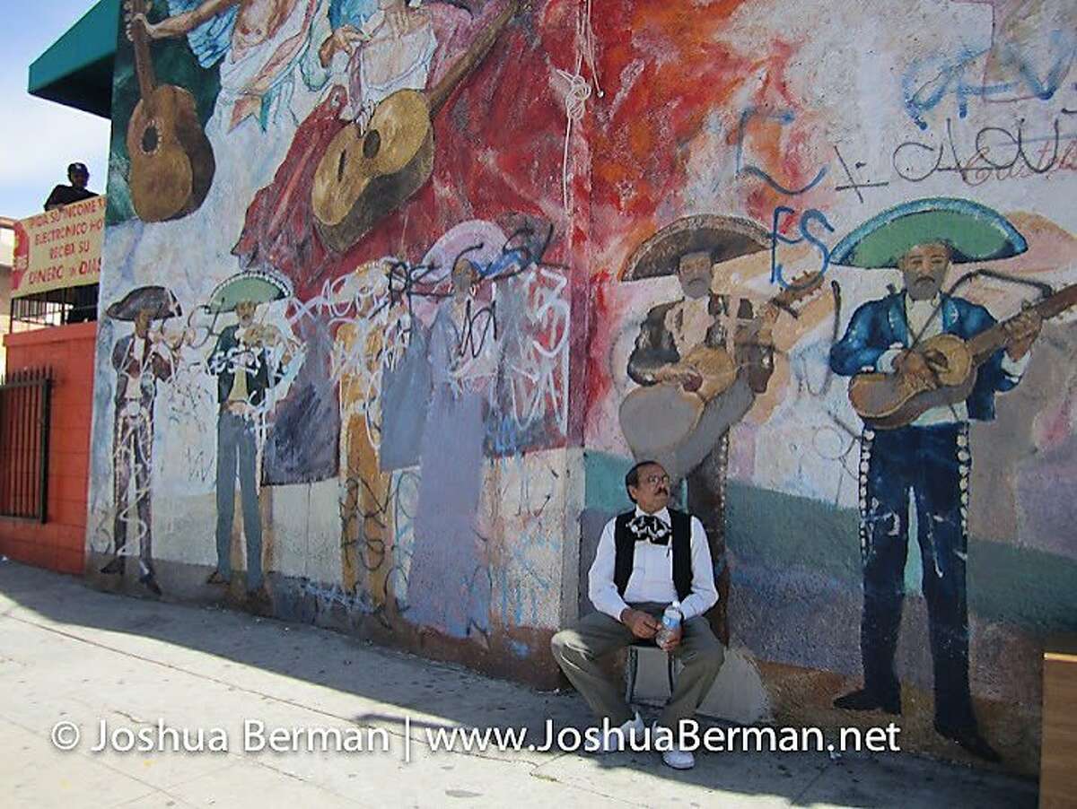 A musician sits below a mural in Mariachi Plaza de Los Angeles (in East Los Angeles), a public square dedicated to mariachi and its players.