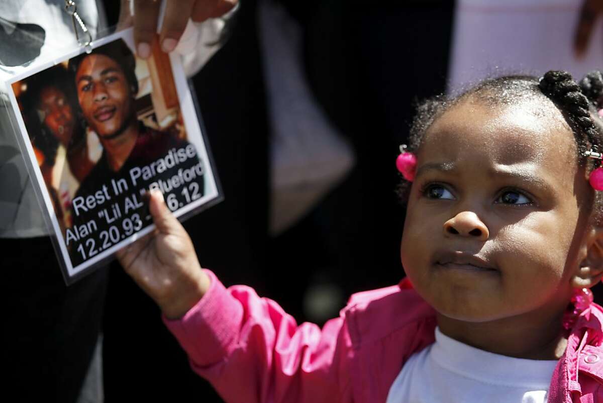 Camari Carter, 2 years old, pulls on a tag worn by her mother of Alan Blueford, as the family addresses the media outside the Alameda County Sheriffs Coroner's Office, Thursday July 19, 2012 in Oakland, Calif. The Blueford family are asking for a copy of their son Alan Blueford's autopsy report and demanding justice for his killing. Alan, 18 years old, was killed on May 6th by an Oakland police office in East Oakland.
