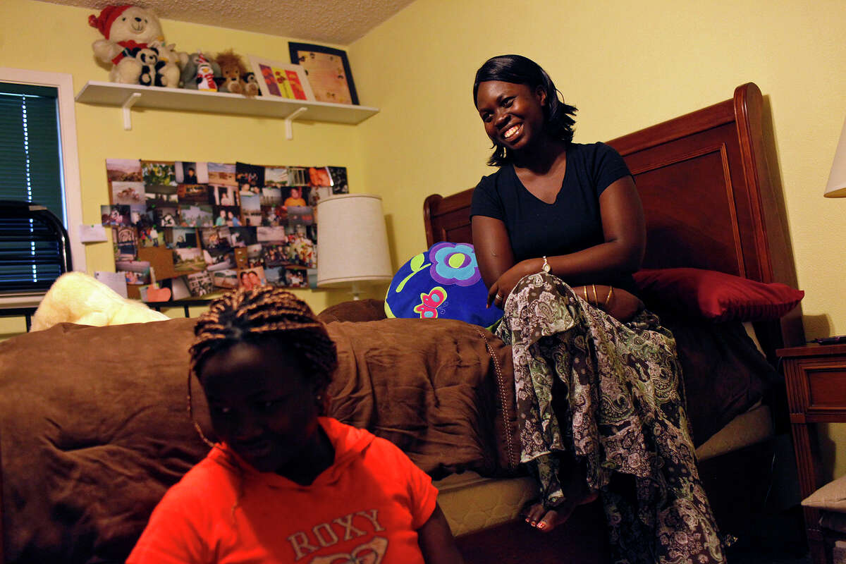 Faida Lambere, 17, and her sister, Kito Feza, 13, sit in their new bedroom on Saturday, July 21, 2012, at the home of Scott and Nancy Hagerup, where they are living since being evicted from their San Antonio apartment Tuesday.