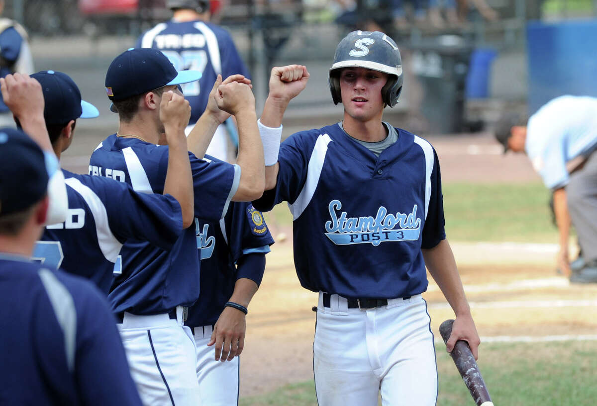 Stamford's Kyle DiVico is greeted by teammates after bringing in a run as Stamford hosts Newington in a Senior American Legion state tournament game at Cubeta Stadium in Stamford, Conn., July 23, 2012.