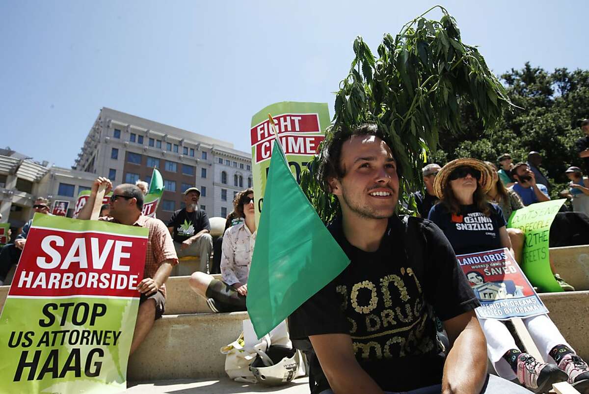 Josh Hewitt, center, joins other protesters at Frank Ogawa Plaza in Oakland, Calif. on Monday, July 23, 2012, as they await the arrival of President Barack Obama.