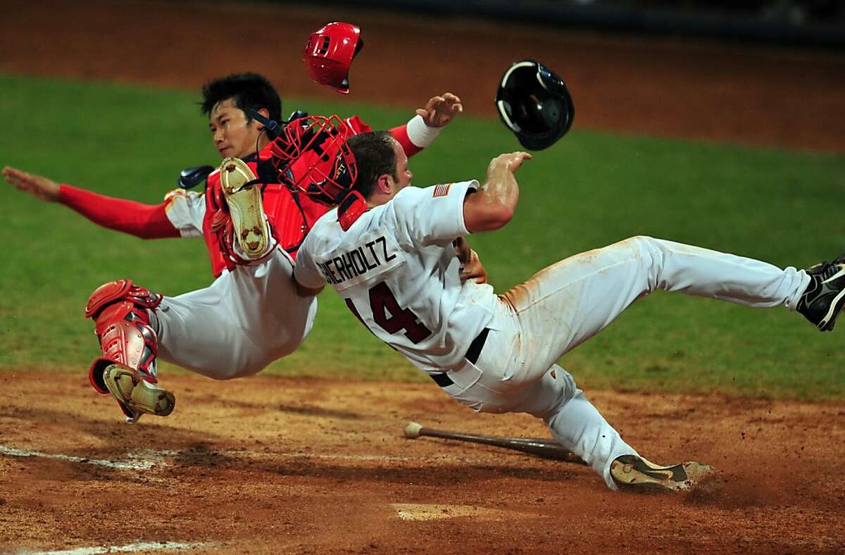 Nate Schierholtz (R) of the US barrells into Chinese catcher Yang Yang (L) to score off a hit by Terry Tiffee in their men's preliminary round baseball game at the Wukesong Baseball Venue during the 2008 Beijing Olympic Games on August 18, 2008. The US won 9-1.