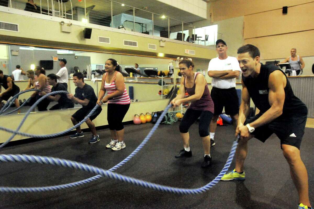 Sport & Wellness general manager Scott Robinson, right center, looks on as Max Barry, right, leads a battling ropes exercise at the Danbury sports club Tuesday, July 24, 2012.