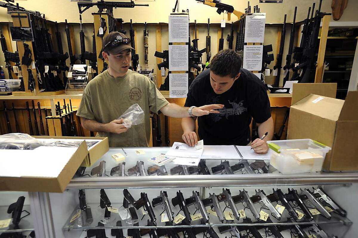 As new guns arrive and are unpacked, employees Aaron Grant(L) and Steve Eichhorn enter the weapons serial numbers in to a log book at Gun Vault in Mountain View, CA July 25th, 2012.