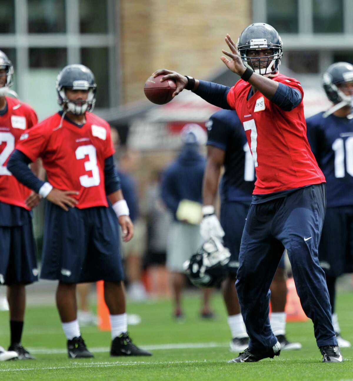 Seahawks quarterback Russell Wilson, (3) looks on as quarterback Tavaris Jackson, right, passes the ball.