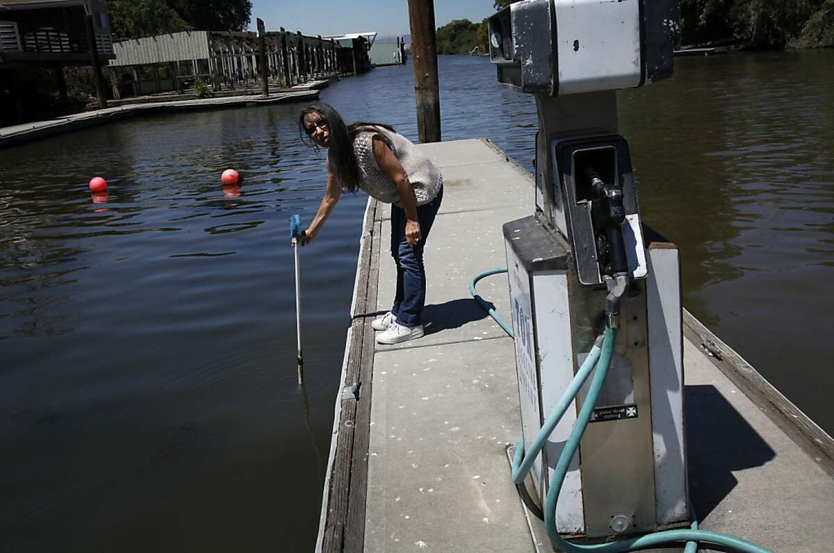 Korinne Flowers, who owns the Tracy Oasis Marina-Resort, uses a pole to show how low the water level is in Tracy, Calif., Friday, July 27, 2012. Flowers is worried any plan to move water to existing pumps that supply water to Southern California, the Central Valley and the Bay Area will lower the water even more and hurt business.