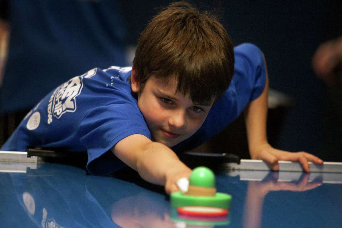 Felix Grabmayr, 9, stretches for the puck as he warms up during the air hockey world championships Saturday at the SRO Family Sports Bar and Cafe. Felix came with his dad and older brother from Seattle and competed in his very first youth division tournament.
