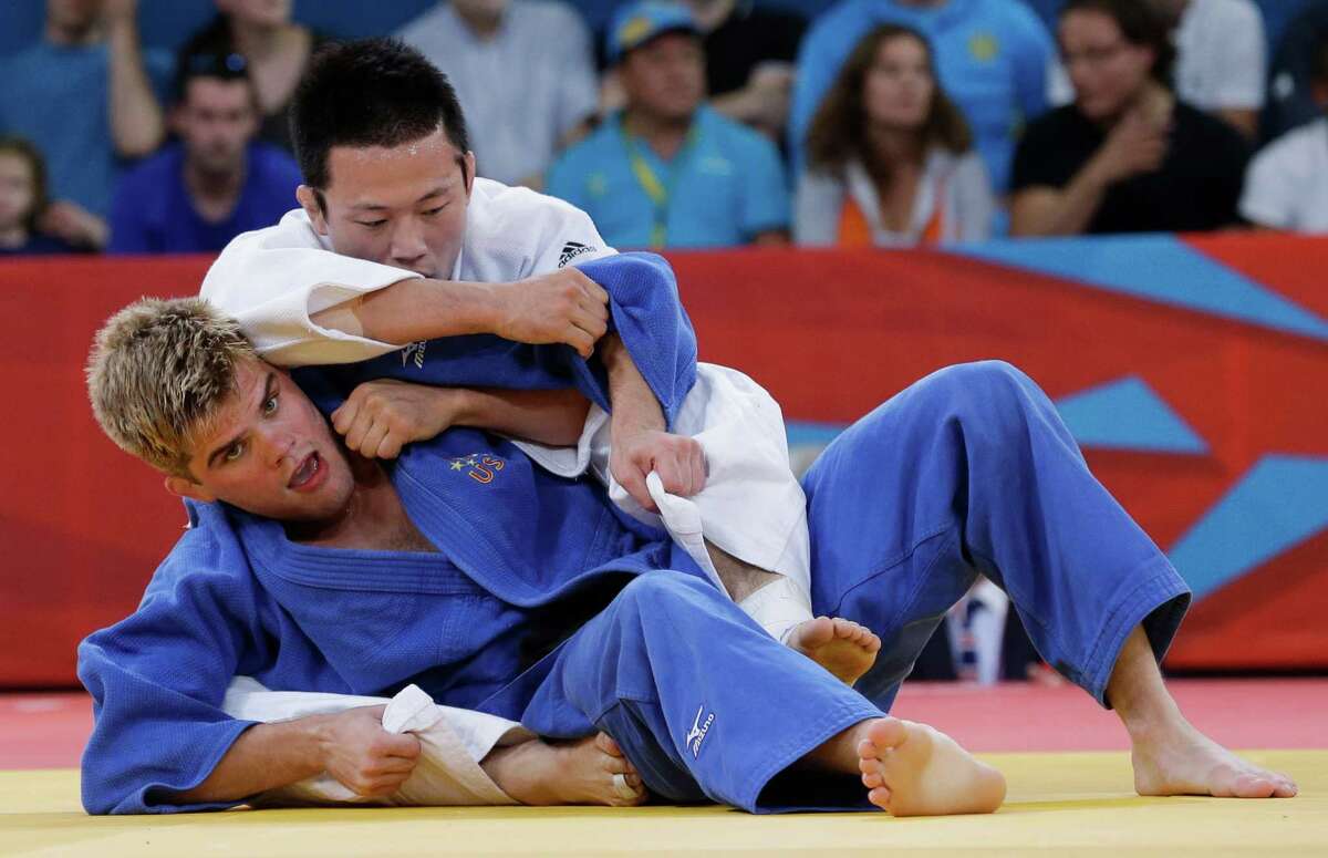 Wang Ki-chun of South Korea, top, competes with Nicholas Delpopolo of the United States during the men's 73-kg judo competition at the 2012 Summer Olympics, Monday, July 30, 2012, in London. (AP Photo/Paul Sancya)