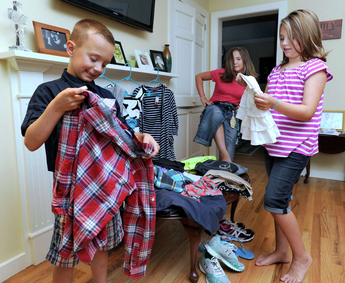 From left, the Harty children, Collin, 7, Grace, 10, and Abbey, 8, go through a pile of clothes recently purchased for when they head back to school.