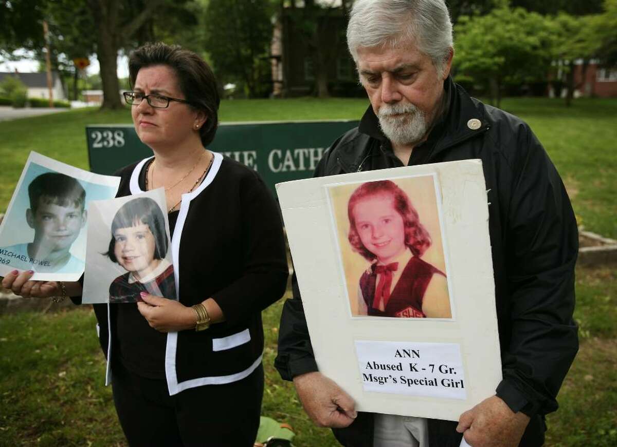 FILE PHOTO Helen McGonigle, left of Brookfield, and Jim Alvord of Norwalk, hold photos of sexual abuse victims during a May press conference outside the Catholic Center at 238 Jewett Avenue in Bridgeport. Protesters delivered a letter to Bishop William Lori asking that the diocese not appeal a Supreme Court decision to release documents in clergy sex abuse cases.
