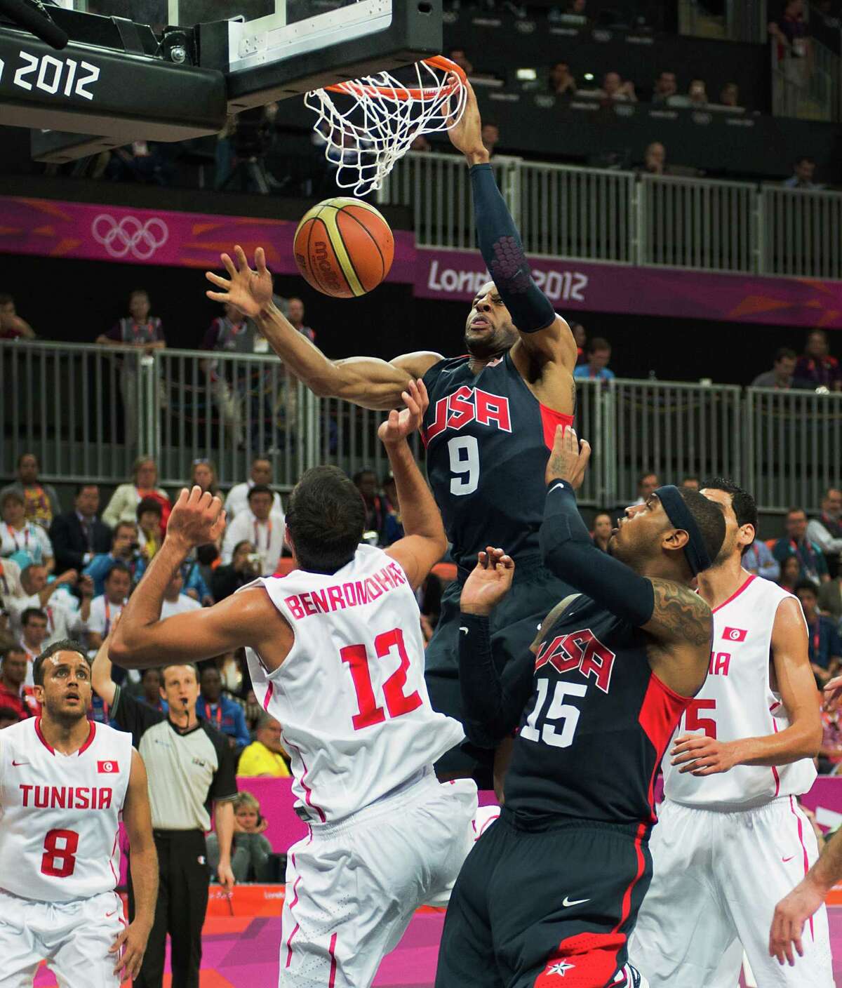 USA's Andre Iguodala dunks the ball over Tunisia's Makram Ben Romdhane during a men's preliminary round basketball game at the 2012 London Olympics on Tuesday, July 31, 2012.