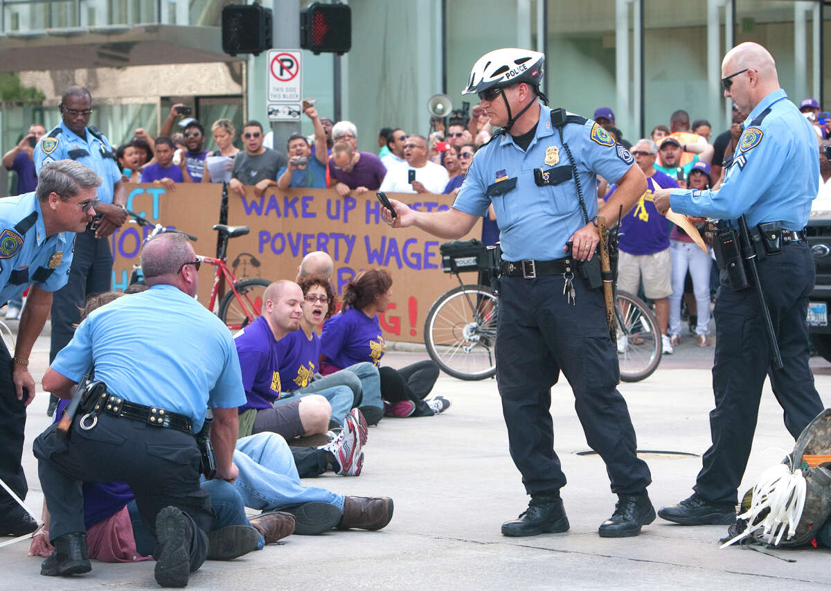 Protesters sit in the intersection of Dallas and Smith Streets in protest of janitors' current wages Wednesday, August 1, 2012, in Houston. Civil rights and labor activists are currently demonstrating civil disobedience and supporting janitors who are entering their fourth week of an unfair labor practices strike.