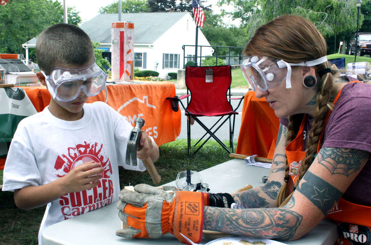 Nicholas Lucas, 7, of New Milford engages in a woodworking project with assistance from Home Depot staffer Amy Rosebrock of Warren during the 45th annual New Milford Village Fair Days on the Village Green. July 28, 2012