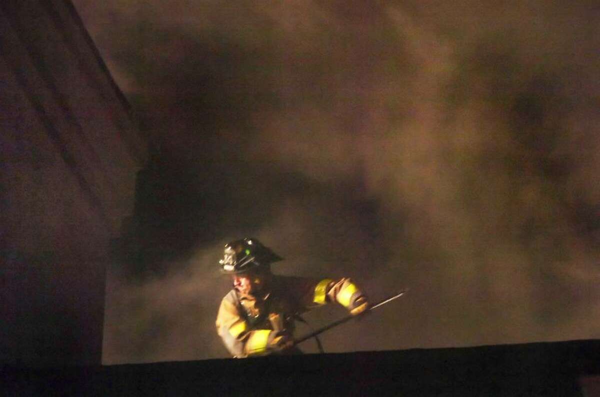 A Firefighter battles a structure fire on the rooftop of the Old Greenwich Gables condominium complex at 51 Forest Avenue late Tuesday, Dec. 1, 2009. The fire spread through several units displacing numerous residents and causing extensive damage to exterior of the building; the battle to contain it went well into the night.