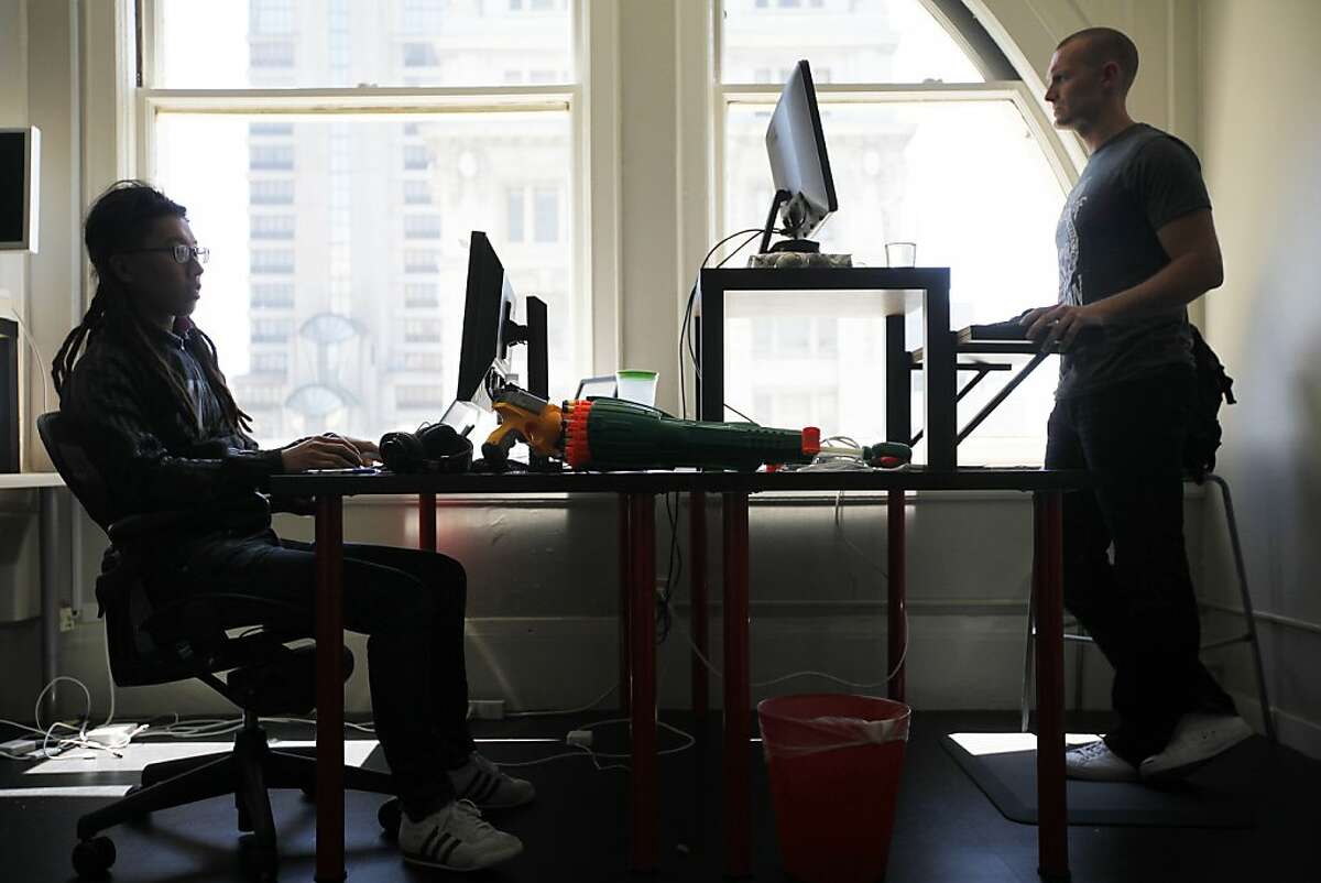 Derek P. Collins (right) prefers to stand while Nemo Chu rather sits in his ergonomical chair during work. A growing number of workplaces are letting their employees use standing desks to alleviate back pain and improve blood circulation. Web analytics company KISSMetrics is one of them in San Francisco, Calif. on Monday, July 30, 2012.