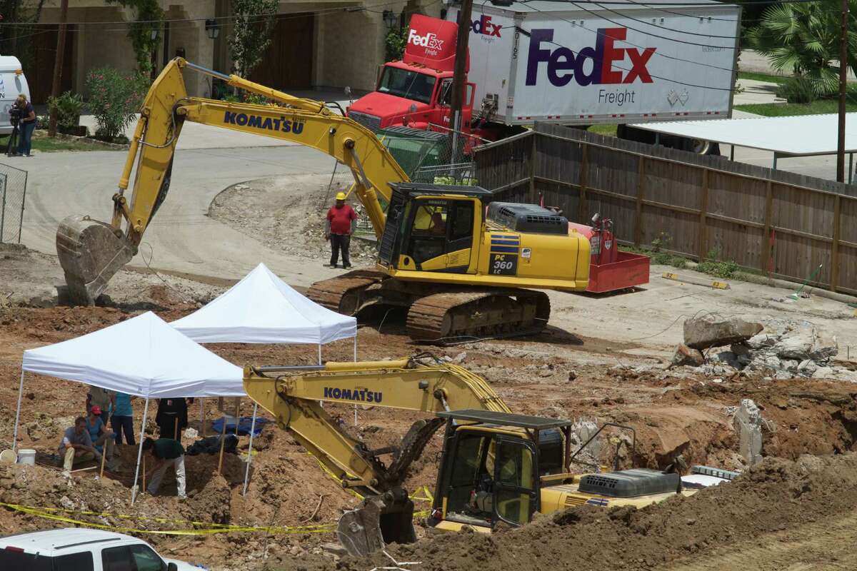 Construction continues Thursday as investigators excavate for bones under white canopies at a building site near Memorial Park where human remains were found.