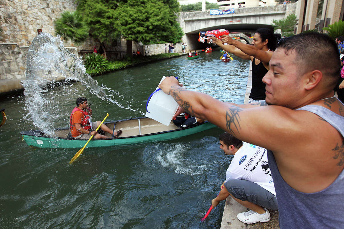 Carlos Delgado tosses a bucket of water to a group of friends in a canoe at the 44th annual Ford Canoe Challenge along the River Walk on Saturday, August 4, 2012. About 100 teams that included Boy Scouts and Girls Scouts, corporate and celebrity participants took part in one of the oldest events held on the river. Delgado and his friends made the event more challenging by adding the element of water guns and tossed water to their friends race along the course.